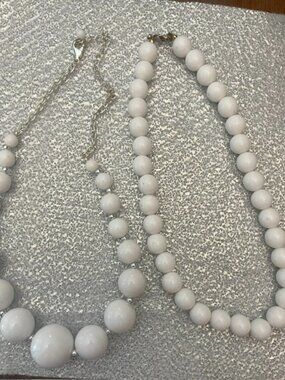 Two white bead necklaces with a graduated size design and silver-tone accents.